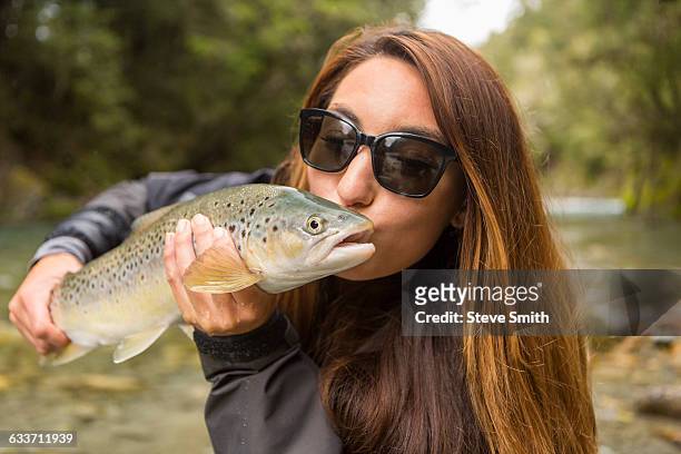 caucasian woman kissing fish in remote river - woman awards 2015 stock-fotos und bilder