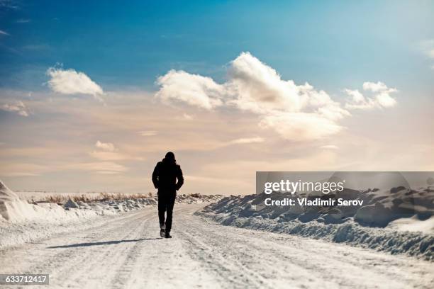 caucasian man walking in snowy landscape - man standing in the snow stock-fotos und bilder