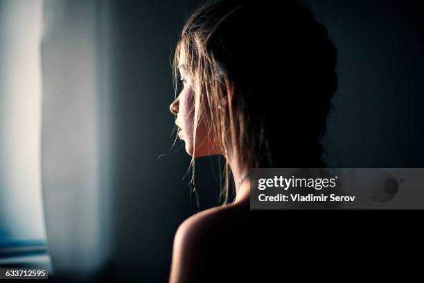 caucasian teenage girl looking out window - depressione foto e immagini stock