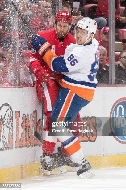 Nikolay Kulemin of the New York Islanders checks Niklas Kronwall of the Detroit Red Wings into the boards during an NHL game at Joe Louis Arena on...