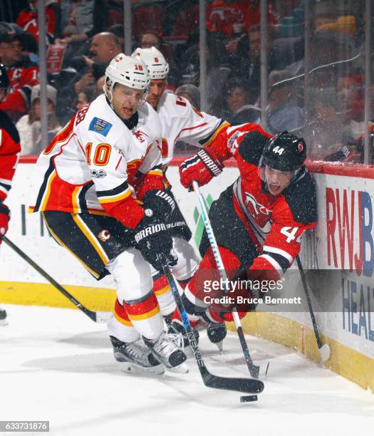 Kris Versteeg of the Calgary Flames and Miles Wood of the New Jersey Devils battle for the puck during the second period at the Prudential Center on...