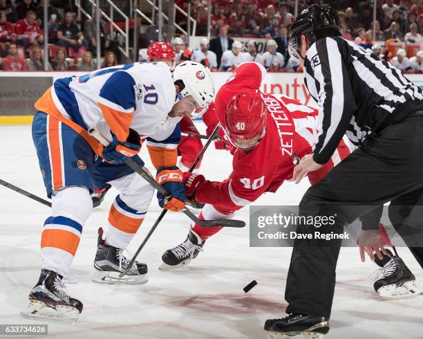Alan Quine of the New York Islanders faces off against Henrik Zetterberg of the Detroit Red Wings during an NHL game at Joe Louis Arena on February...