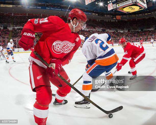 Dylan Larkin of the Detroit Red Wings controls the puck along the boards as teammate Frans Nielsen battles Nick Leddy of the New York Islanders...