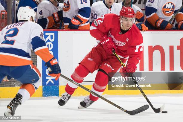 Andreas Athanasiou of the Detroit Red Wings skates up ice with the puck in front of Nick Leddy of the New York Islanders during an NHL game at Joe...