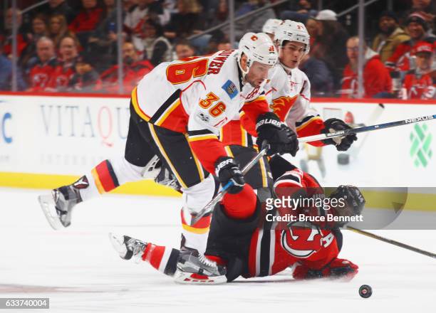 Troy Brouwer of the Calgary Flames checks Adam Henrique of the New Jersey Devils during the third period at the Prudential Center on February 3, 2017...