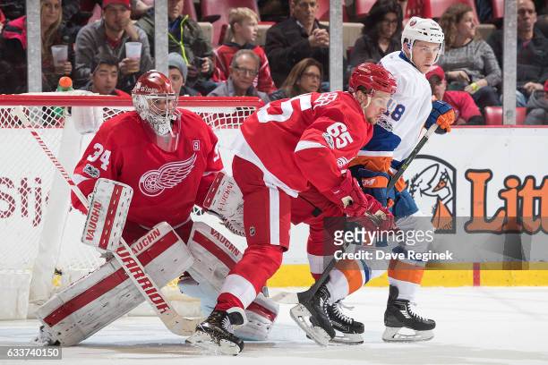 Ryan Strome of the New York Islanders battles for position with Danny DeKeyser of the Detroit Red Wings in front of goaltender Petr Mrazek of the...