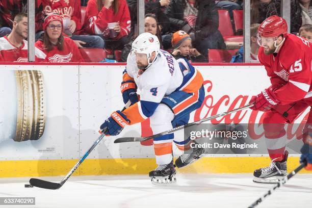 Dennis Seidenberg of the New York Islanders skates with the puck followed by Riley Sheahan of the Detroit Red Wings during an NHL game at Joe Louis...