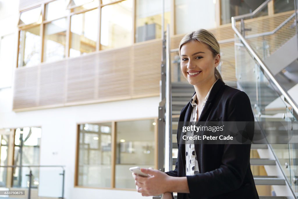 Positive woman holding phone wearing suit