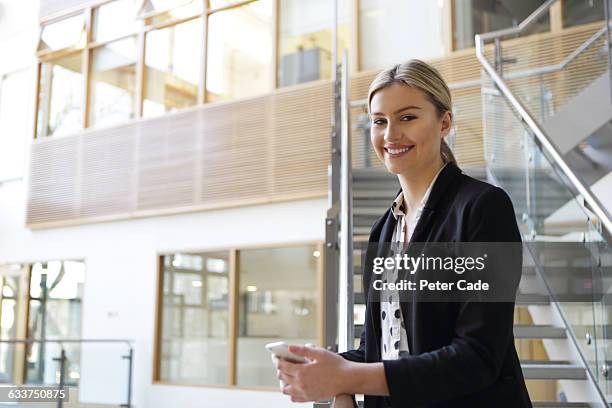 positive woman holding phone wearing suit - girl in office stock pictures, royalty-free photos & images