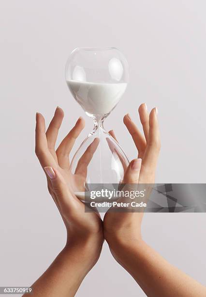 hands holding hourglass - hourglass stock pictures, royalty-free photos & images
