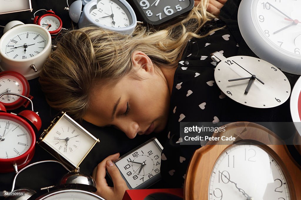 Woman asleep surrounded by clocks