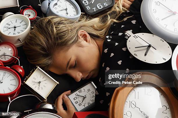 woman asleep surrounded by clocks - väckarklocka bildbanksfoton och bilder