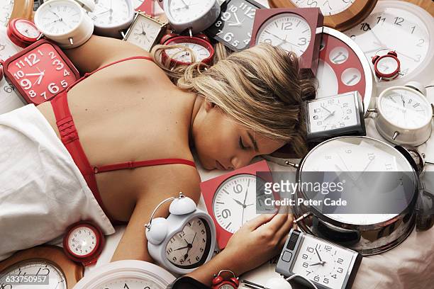 young woman asleep on pile of clocks - alertness stock pictures, royalty-free photos & images