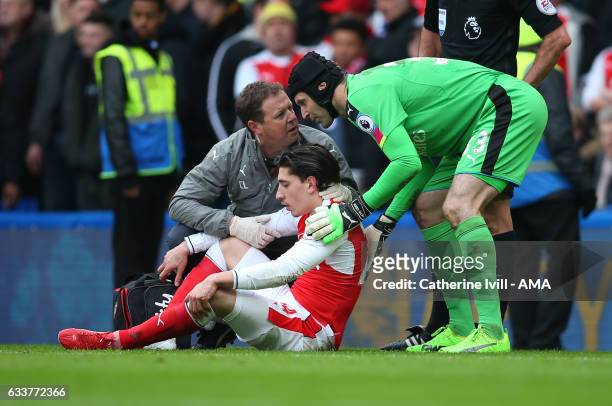 The Arsenal medic confers with Petr Cech of Arsenal as Hector Bellerin of Arsenal is treated for an injury during the Premier League match between...