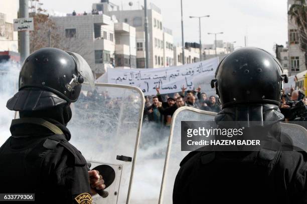 Palestinian policemen stand opposite to demonstrators during a protest against a decision by the Palestinian Authority to grant a public land to the...