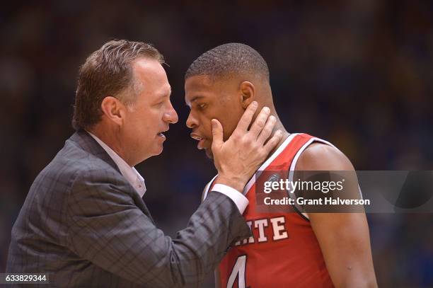 Head coach Mark Gottfried of the North Carolina State Wolfpack talks with Dennis Smith Jr. #4 of the North Carolina State Wolfpack during their win...