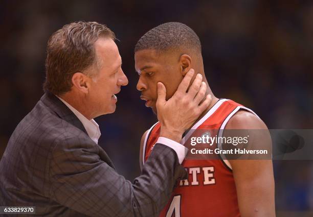 Head coach Mark Gottfried of the North Carolina State Wolfpack talks with Dennis Smith Jr. #4 of the North Carolina State Wolfpack during their win...