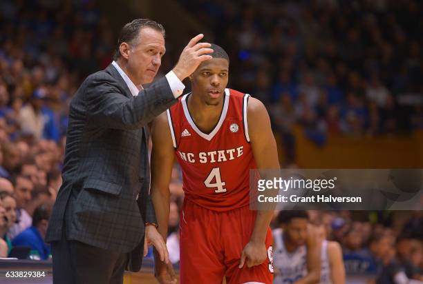 Head coach Mark Gottfried of the North Carolina State Wolfpack talks with Dennis Smith Jr. #4 of the North Carolina State Wolfpack during their win...
