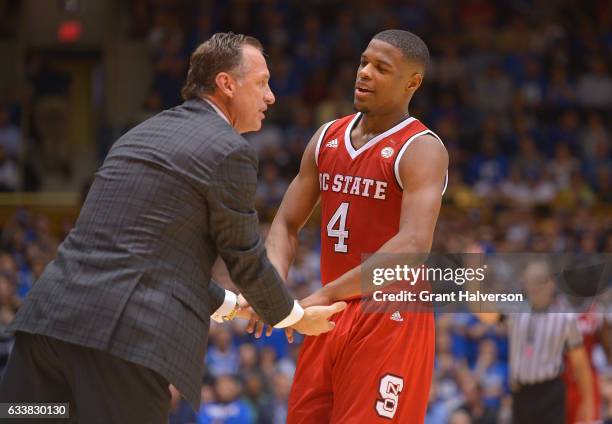 Head coach Mark Gottfried of the North Carolina State Wolfpack talks with Dennis Smith Jr. #4 of the North Carolina State Wolfpack during their win...