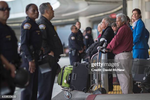 Arriving international travelers cross a police line separating pro- and anti-demonstrators of a ruling by a federal judge in Seattle that grants a...