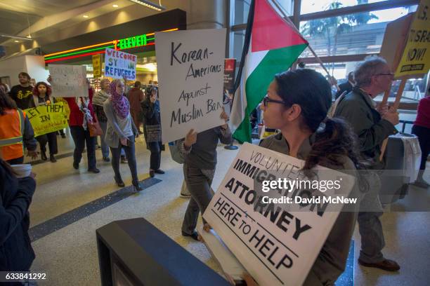 Demonstrators pass a volunteer immigration attorney as they march in support of a ruling by a federal judge in Seattle that grants a nationwide...