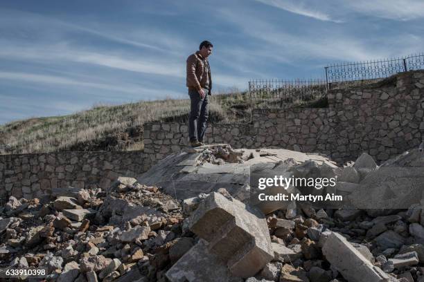 An Assyrian Catholic Iraqi man stands on top of the destroyed dome of the tomb of Mar Behnam and Mart Sarah at the Mar Behnam monastery on February...