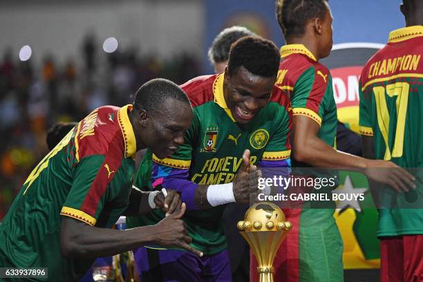 Cameroon's goalkeeper Fabrice Ondoa and Cameroon's forward Vincent Aboubakar react to the winner's trophy after Cameroon beat Egypt 2-1 in the 2017...