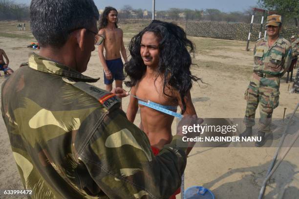 Potential Indian Army recruit with long hair, in a predominantly Sikh area where men traditionally never cut their hair, has his chest measured...