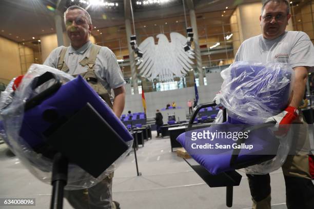 Workers carry chairs out of the plenary hall of the Bundestag in preparations for the upcoming session of the Federal Assembly to elect a new...