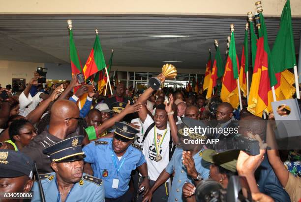 Fans cheer as Cameroon's team captain and forward Benjamin Moukandjo holds up the winner's trophy as he and the national football team arrive home in...