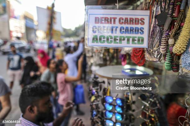 Sign reading "Debit Cards, Credit Cards Accepted" is displayed outside a clothing accessory stall at a street market in Bengaluru, India, on...