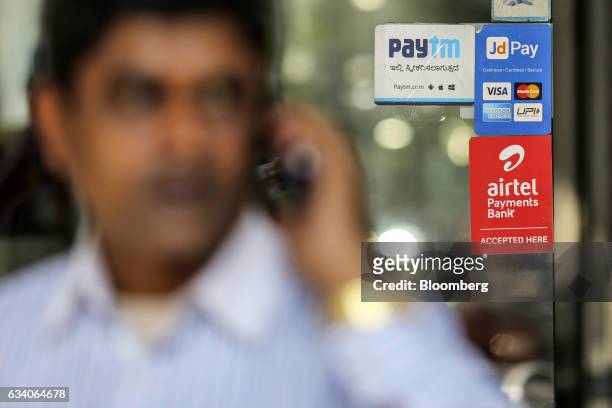 Man speaks on a mobile phone as signage for digital payment services Paytm, operated by One97 Communications Ltd., top left, JD Pay, operated by Just...