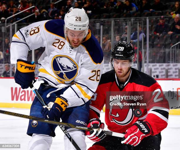 Zemgus Girgensons of the Buffalo Sabres and Damon Severson of the New Jersey Devils battle for the puck during the first period at Prudential Center...