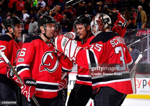 Cory Schneider of the New Jersey Devils is congratulated by his teammates after his team defeated the Buffalo Sabres at Prudential Center on February...