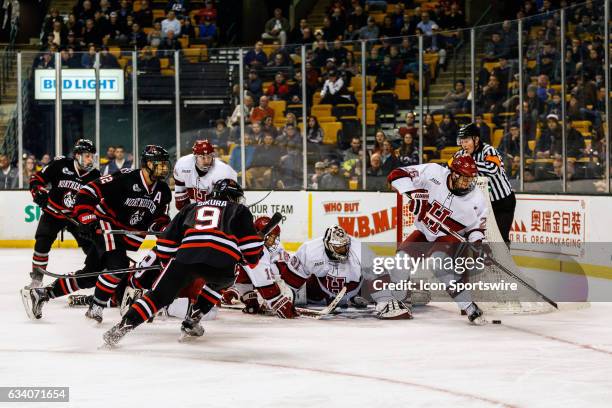 The Crimson fights to clear the a loose puck away from the Huskies during the third period of the Beanpot Tournament semifinals game between the...