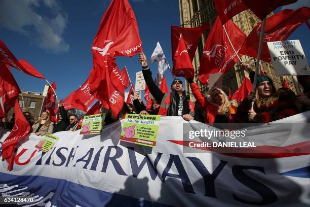 Demonstrators hold placards and wave flags as they protest against the low wages and "poverty pay" of British Airways' staff, outside the Houses of...