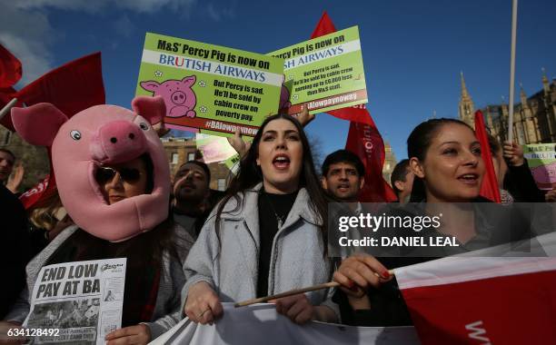 Demonstrators hold placards and wave flags as they protest against the low wages and "poverty pay" of British Airways' staff, outside the Houses of...