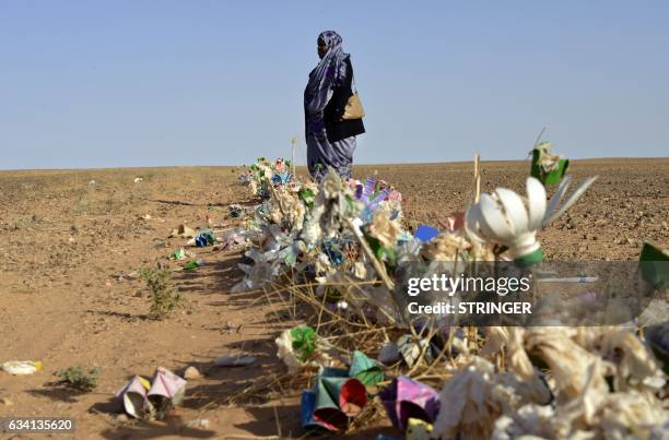 Zghala, a Saharawi woman, stands in front of fake flowers looking at Moroccan soldiers in the Al-Mahbes area as she accompanies her 14-year-old son...