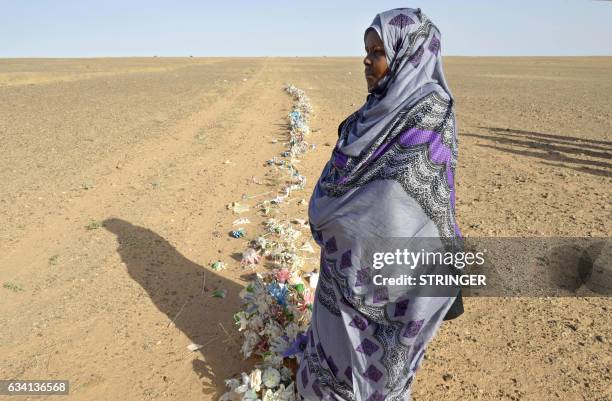 Zghala, a Saharawi woman, stands in front of fake flowers looking at Moroccan soldiers in the Al-Mahbes area as she accompanies her 14-year-old son...