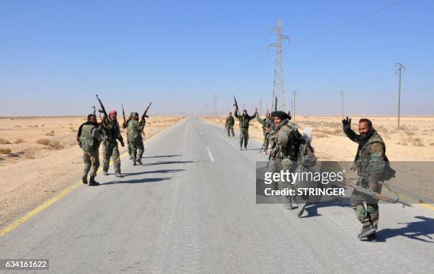 Syrian government forces flash the sign for victory as they approach the strategic Jihar oil fields on the eastern outskirts of Homs on February 7,...