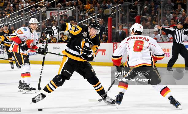 Tom Kuhnhackl of the Pittsburgh Penguins dekes in front of Dennis Wideman of the Calgary Flames at PPG Paints Arena on February 7, 2017 in...
