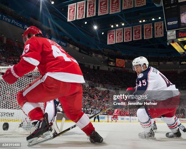 Darren Helm of the Detroit Red Wings and Lukas Sedlak of the Columbus Blue Jackets battle for the puck behind the net during an NHL game at Joe Louis...