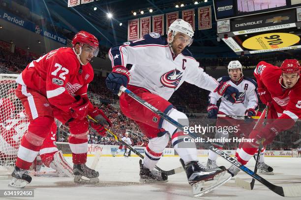 Andreas Athanasiou and Jonathan Ericsson of the Detroit Red Wings battle for the puck with Nick Foligno and Boone Jenner of the Columbus Blue Jackets...