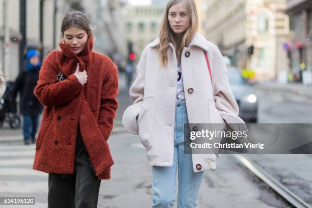 Guest wearing a red wool coat and Tine Andrea wearing a white jacket, red bag, denim jeans on February 7, 2017 in Oslo, Norway.