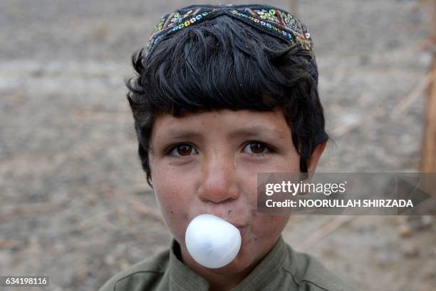 In this photograph taken on January 18 an Afghan child blows a bubble with chewing gum as he stands outside a mud house at a refugee camp on the...