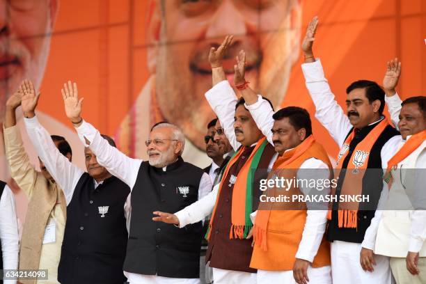 Indian Prime Minister and Bharatiya Janata Party Leader Narendra Modi waves as he stands with party officials during a state assembly election rally...