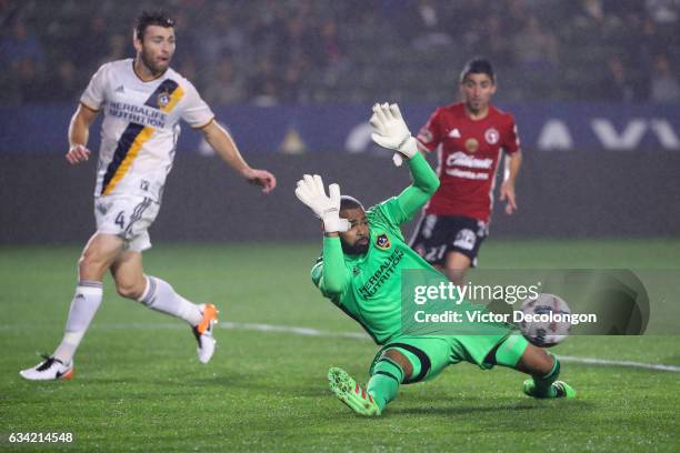 Goalkeeper Clement Diop of the Los Angeles Galaxy makes a save as teammate Dave Romney and Matias Pizano of Club Tijuana look on during the second...