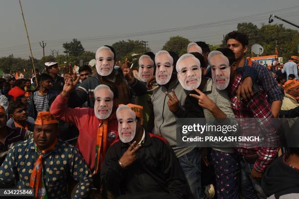 Indian supporters of the Bharatiya Janata Party pose with a mask with an image of Indian Prime Minister Narendra Modi at a state assembly election...