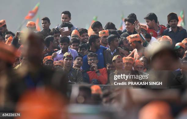 Indian supporters of the Bharatiya Janata Party listen to BJP Leader and Indian Prime Minister Narendra Modi as he speaks during a state assembly...