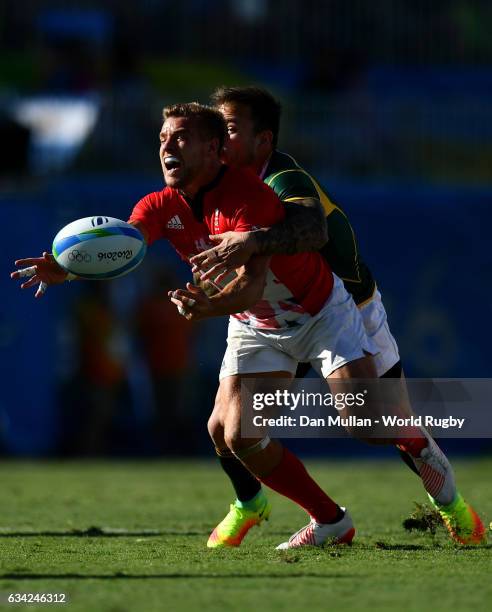 Tom Mitchell of Great Britain offloads as he is tackled by Francois Hougaard of South Africa during the Men's Rugby Sevens semi final match between...